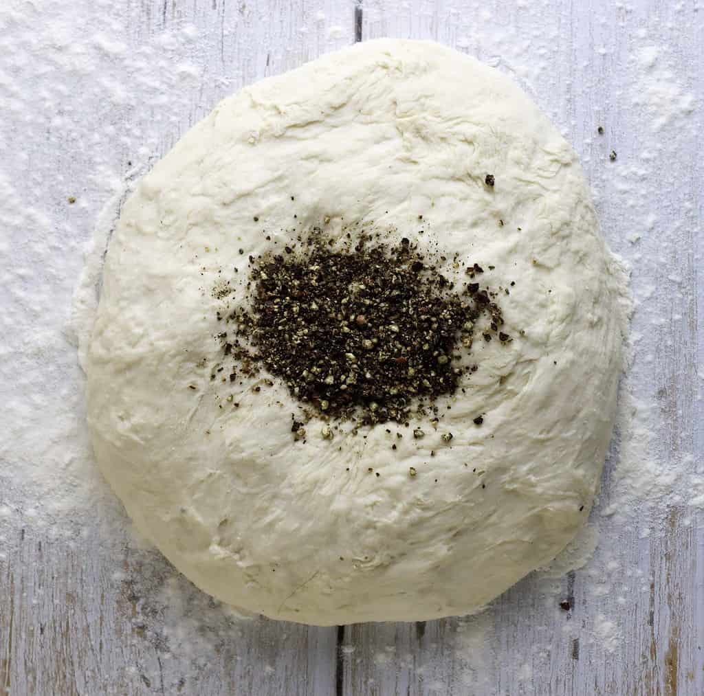 adding black pepper to focaccia douh