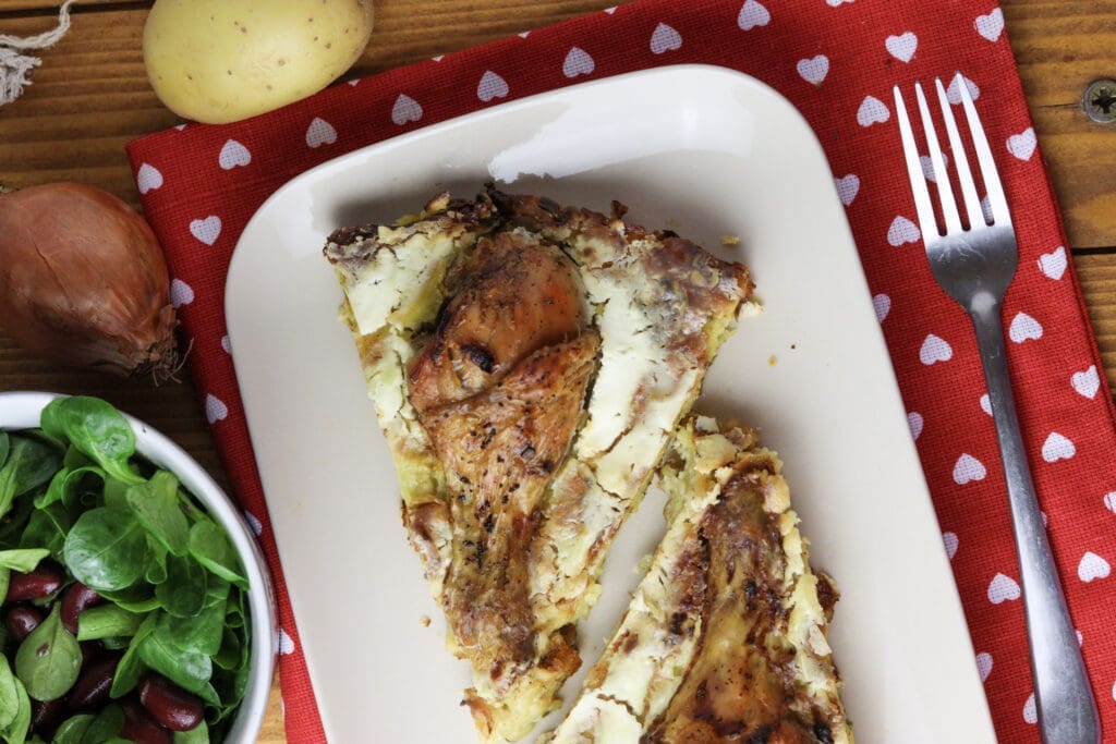 two pieces of baked kljukuša served on a plate with fresh salad