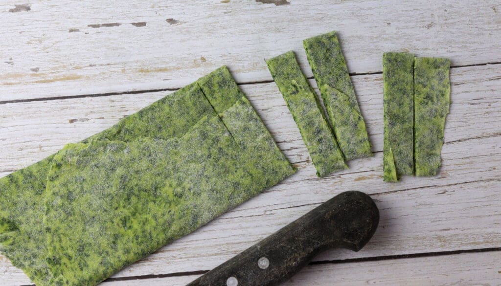 How to cut rolled green wild garlic pasta to noodles like tagliatelle using a sharp knife or pizza cutter 