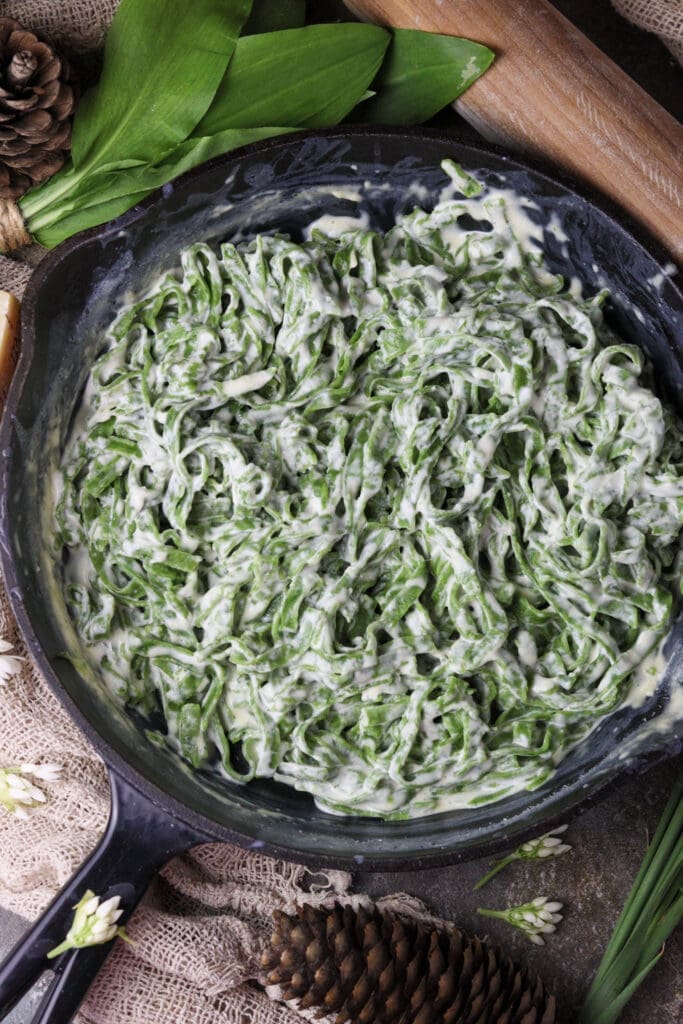 green wild garlic pasta in a pan with a garlic sauce