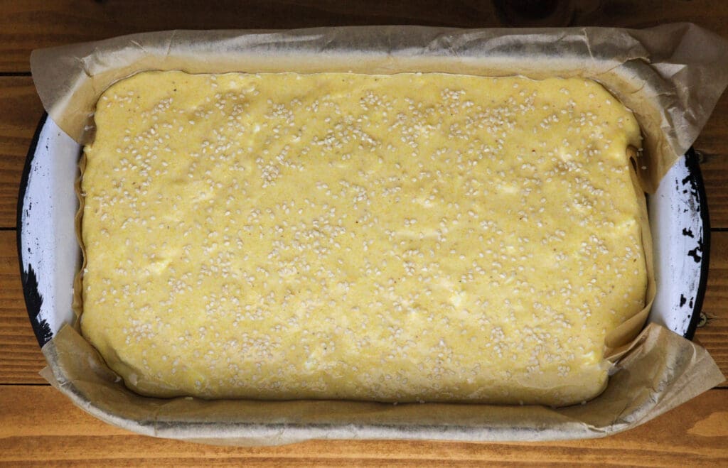 image of polenta bread batter sprinkled with sesame seeds 