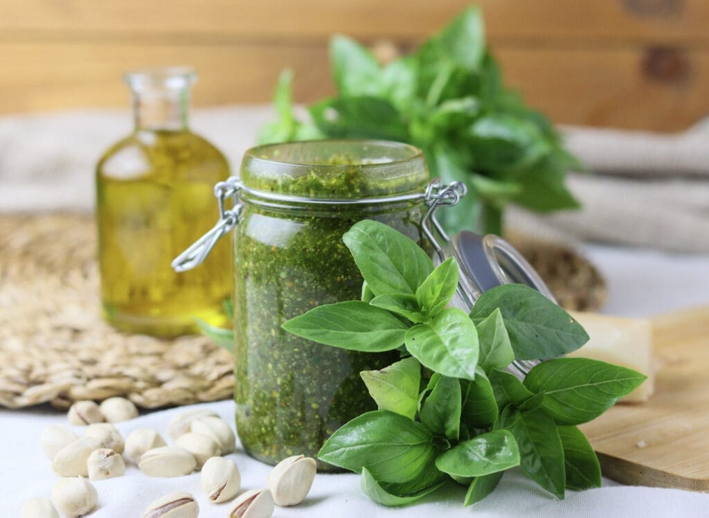 delicios basil pesto with pistachios and grana padano served on the table with olive oil and shelled pistachios