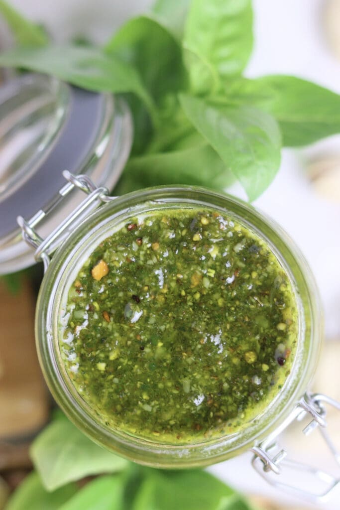 image of an opened jar of basil pesto with pistachios from the top 