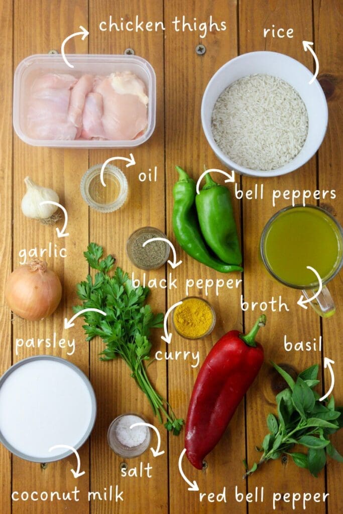 Gathering ingredients for one pot chicken curry and rice: chicken thighs, rice, coconut milk, bell peppers, vegetable broth, an onion, garlic, fresh parsley, basil leaves, salt and black pepper. 