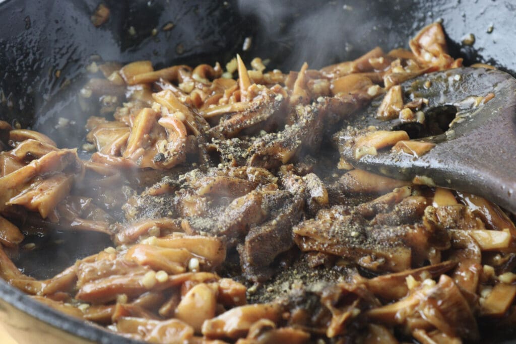 Image of adding black pepper to sauted saffron milk cap mushrooms