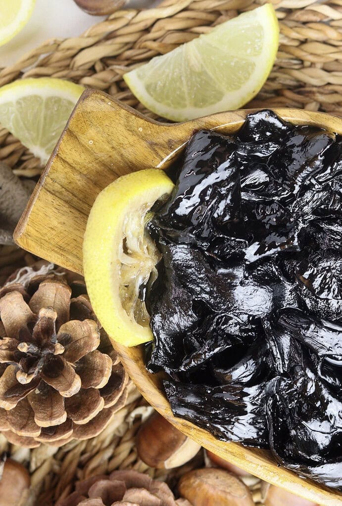 image of black trumpet mushroom jam with lemons and lemon slices for decoration