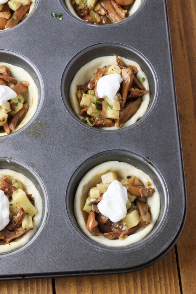 Image showing how to top the tartlets with a dollop of sour cream before baking 