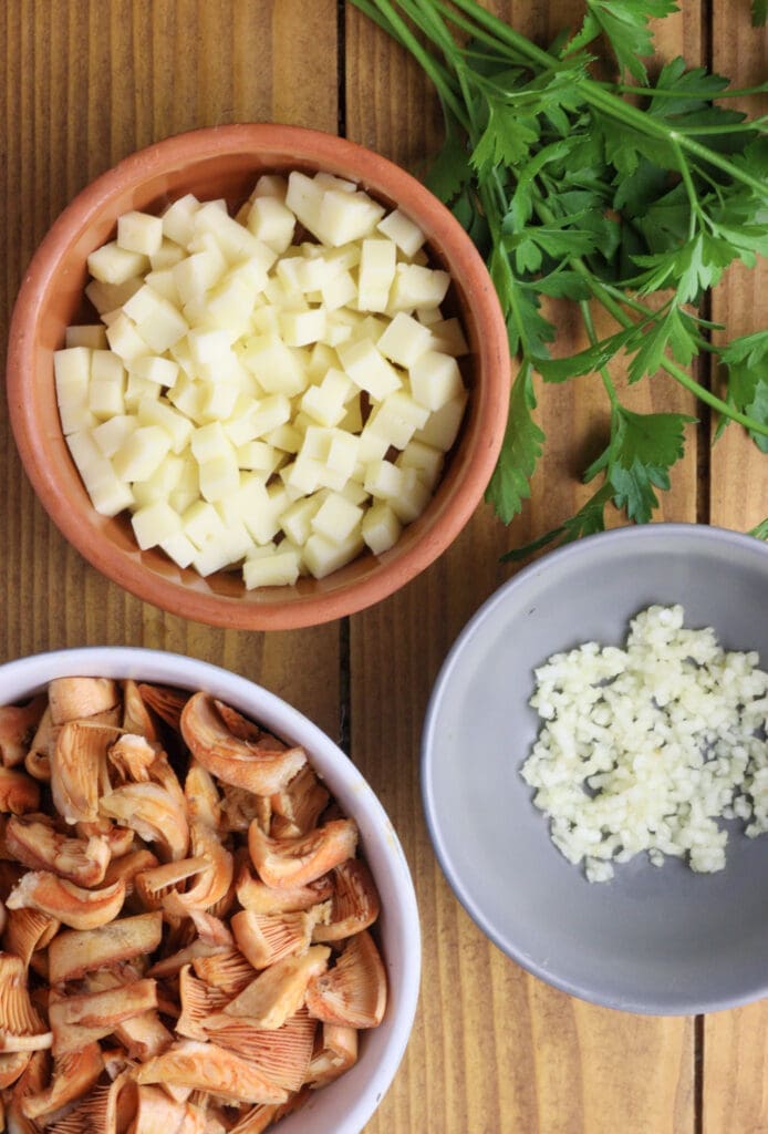 preparing ingredients for tart filling - pieces of cheese, cleaned, chopped saffron milk caps and crushed garlic 