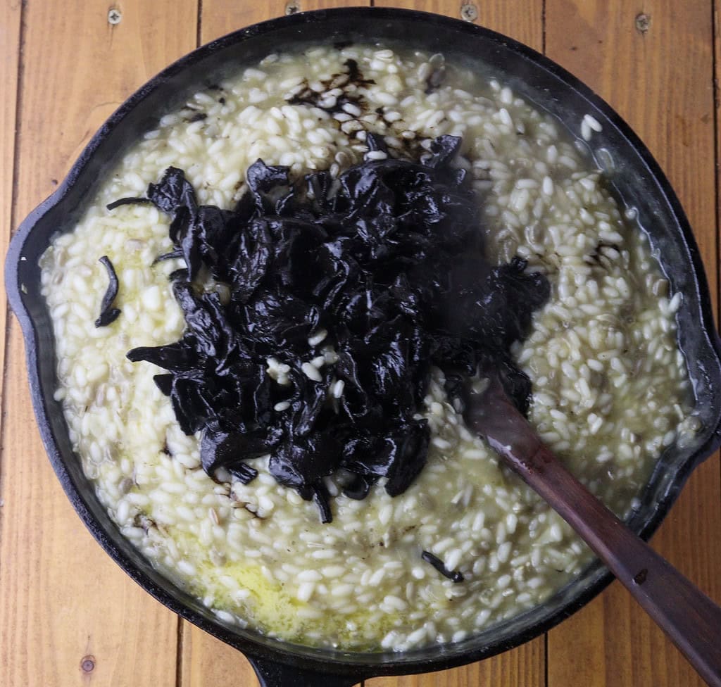 image showing how to add stir-fried black trumpet mushrooms to risotto