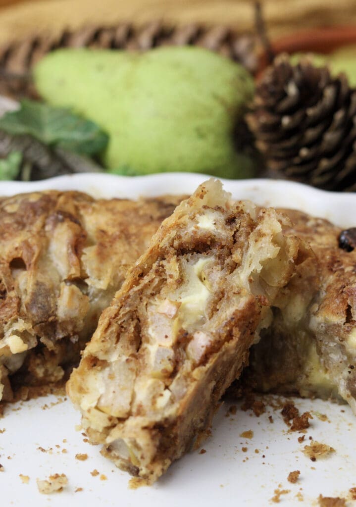 image showing a piece of cheese strudel with pears, raisins and cinnamon