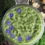 Image of spruce tip pesto in a jar with wild flowers