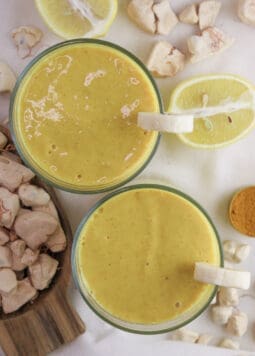 two glasses of healthy baobab smoothie with ginger and baobab fruit in the background