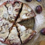 Image of freshly baked buckwheat plum clafoutis with fresh plums in the background