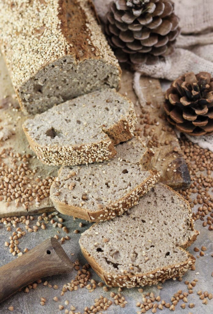 Stack of warm slices of gluten-free buckwheat bread, highlighting the moist crumb and sesame seed crust.