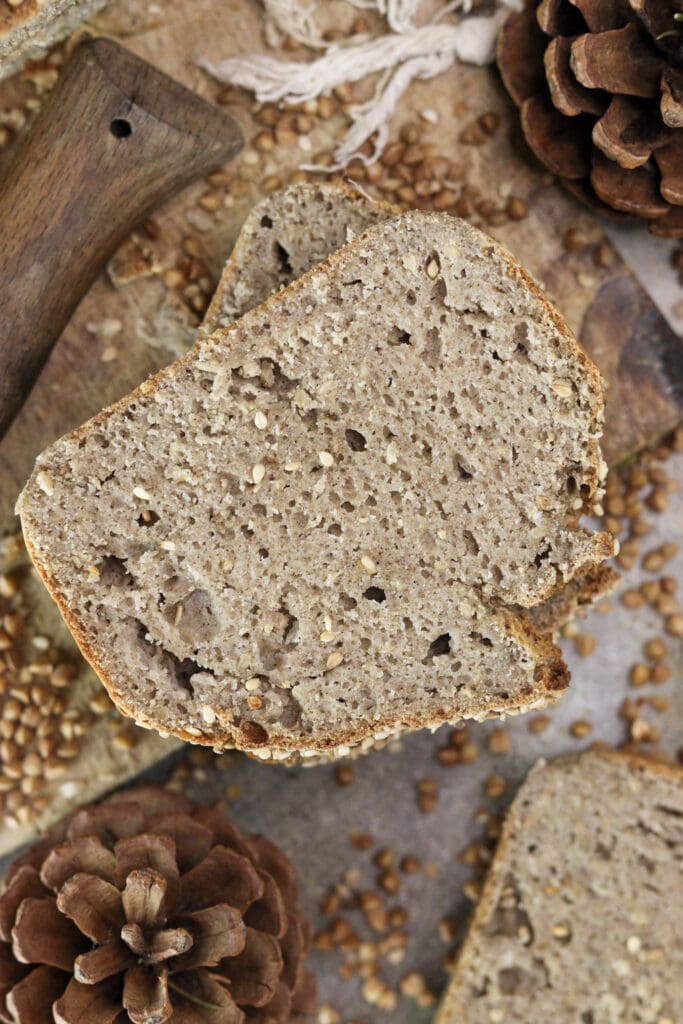 Slices of freshly baked buckwheat soda bread with yogurt and sesame seeds on a wooden board.