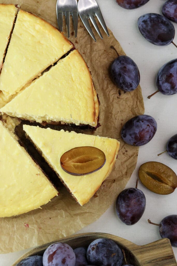 shot from the top - slices plum cheesecake with fresh plums ready to be served. 