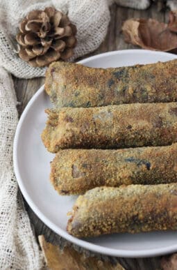 Four fried parasol mushroom rolls stuffed with mozzarella and smoked bacon served on a rustic plate