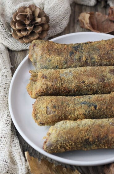 Four fried parasol mushroom rolls stuffed with mozzarella and smoked bacon served on a rustic plate