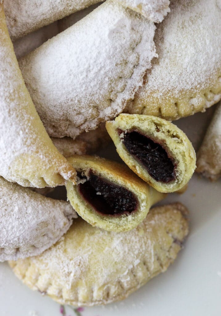 Empanada cookie split in half showing delicious plum jam filling and more cookies in the background