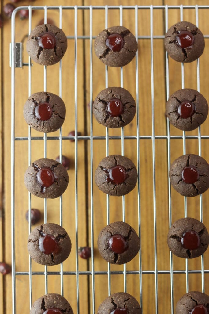 Buckwheat cookies placed on a cooling rack after baked and filled with hot strawberry jam