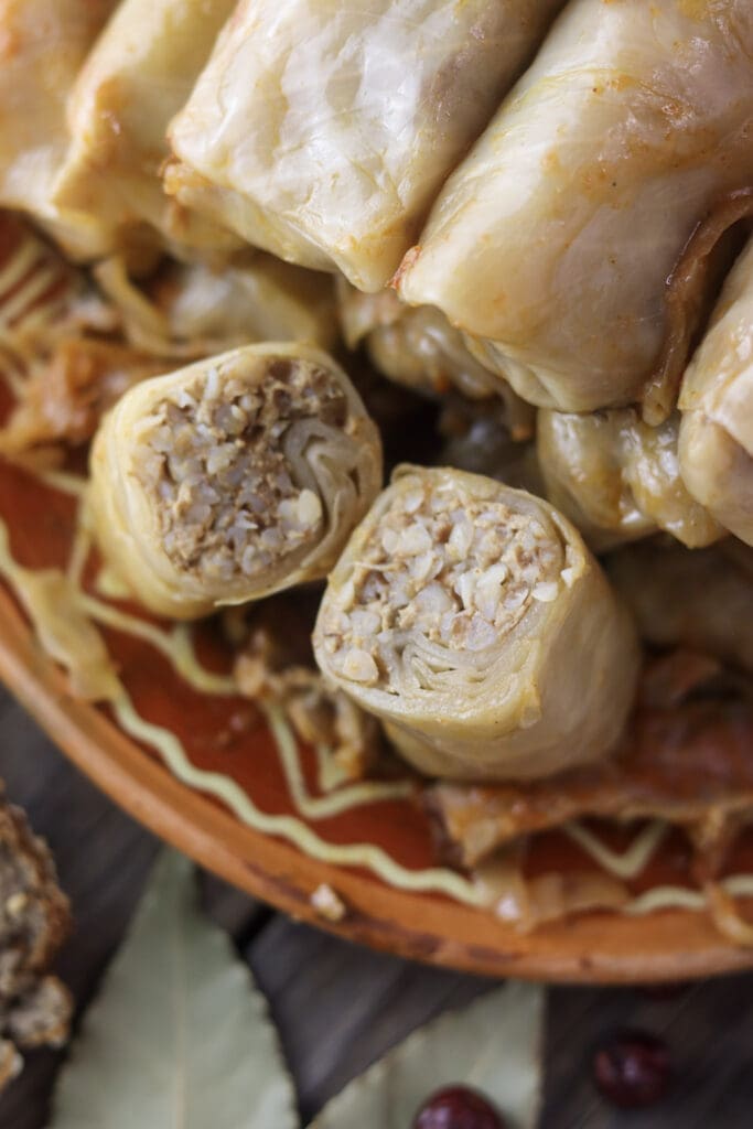sour cabbage rolls with buckwheat filling, one cut open to reveal the meat and grain stuffing