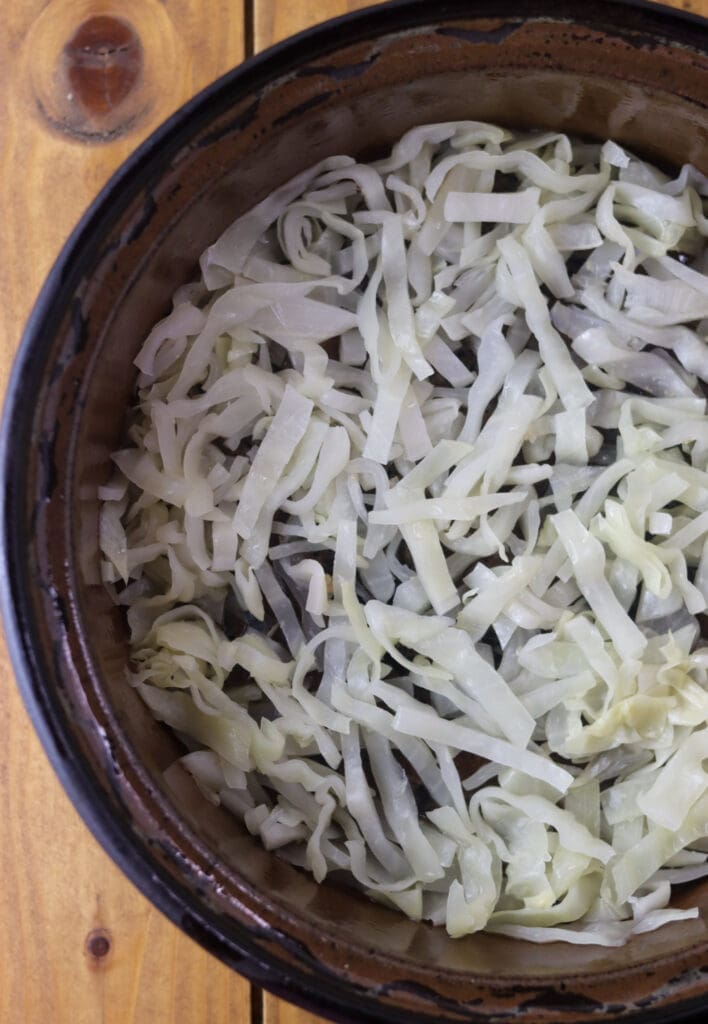 How to place sliced sour cabbage leaves on the bottom of the baking pot before adding the cabbage rolls.
