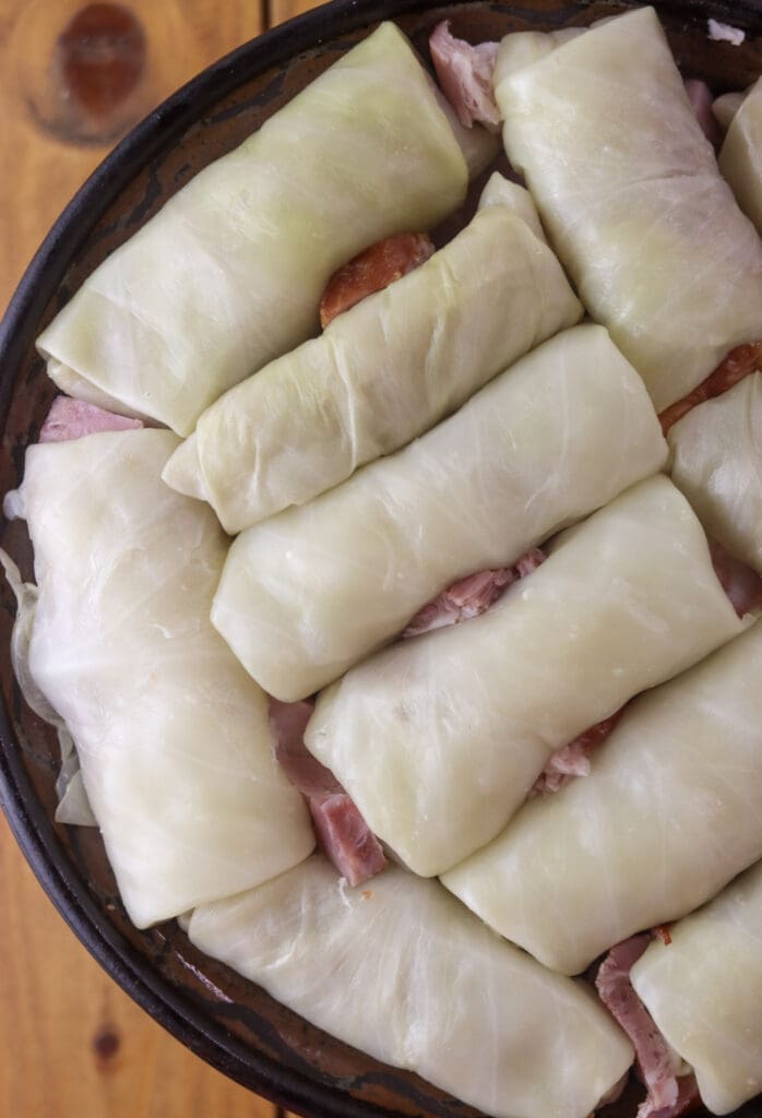 The second layer of stuffed sour cabbage rolls with slices of smoked bacon in between the rolls.