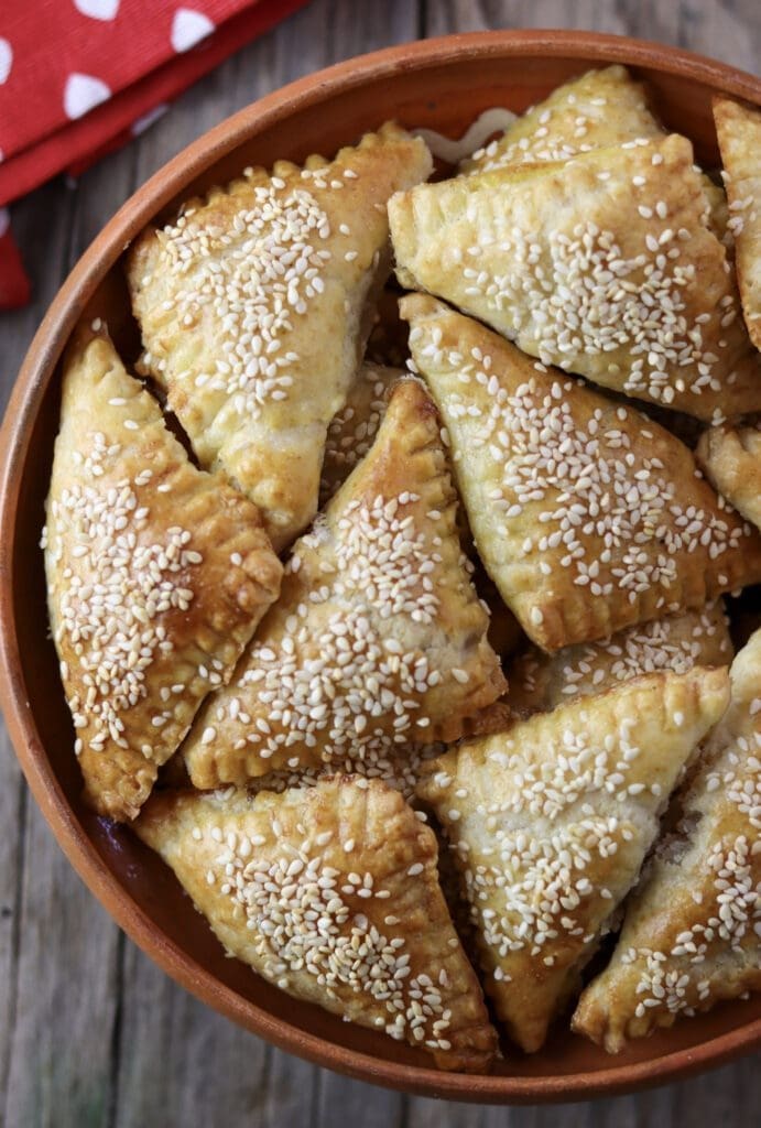 A bowl full of freshly baked crackling cookies with sesame seeds.