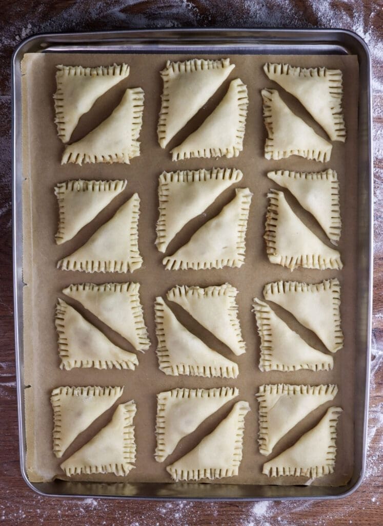 Cookies filled with craclings are placed on parchment paper on a baking tray.