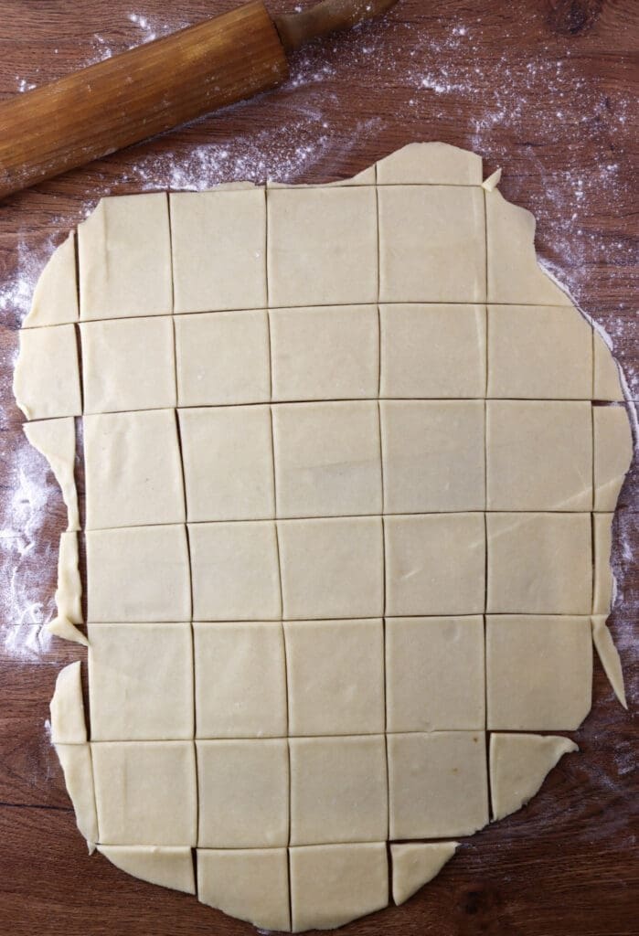 Cutting the dough into squares using a pizza cutter.