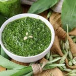 Pesto with wild garlic and toasted pine nuts served in a bowl with wild garlic leaves in the bacground.