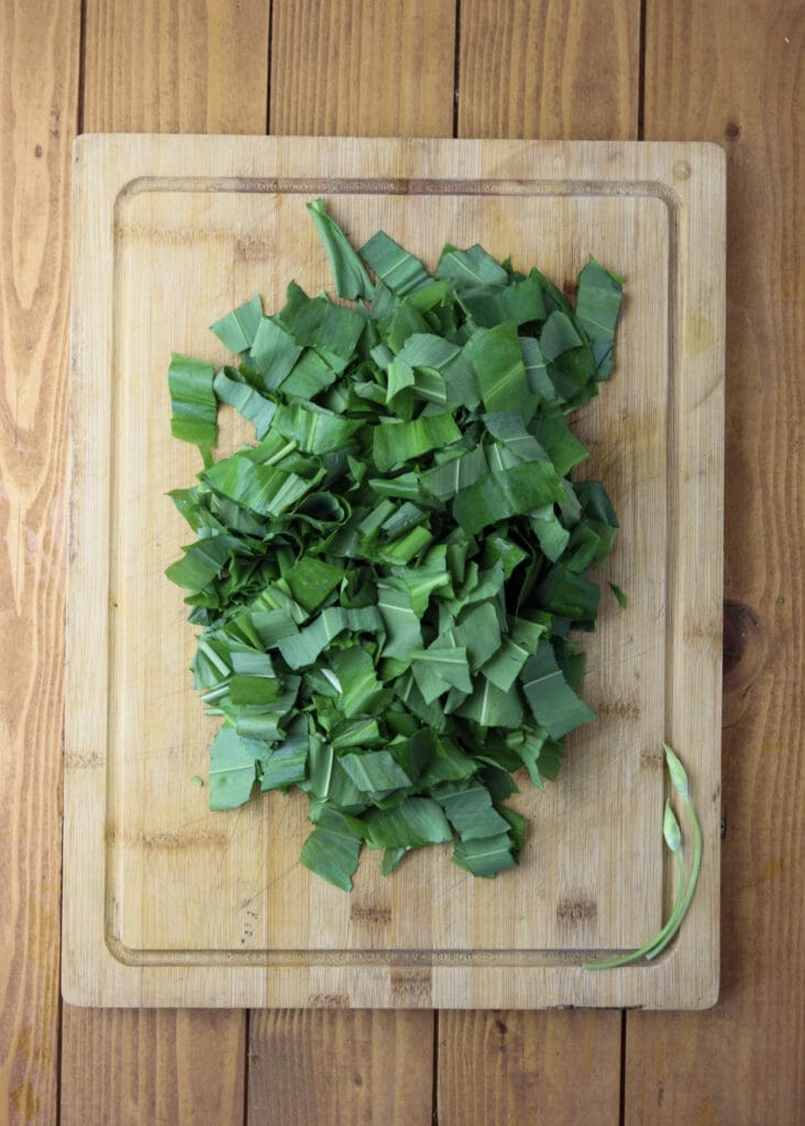 Chopped wild garlic leaves on a wooden cutting board.