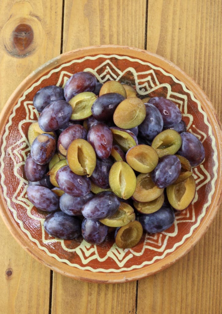 plum halves with removed pits on a clay plate