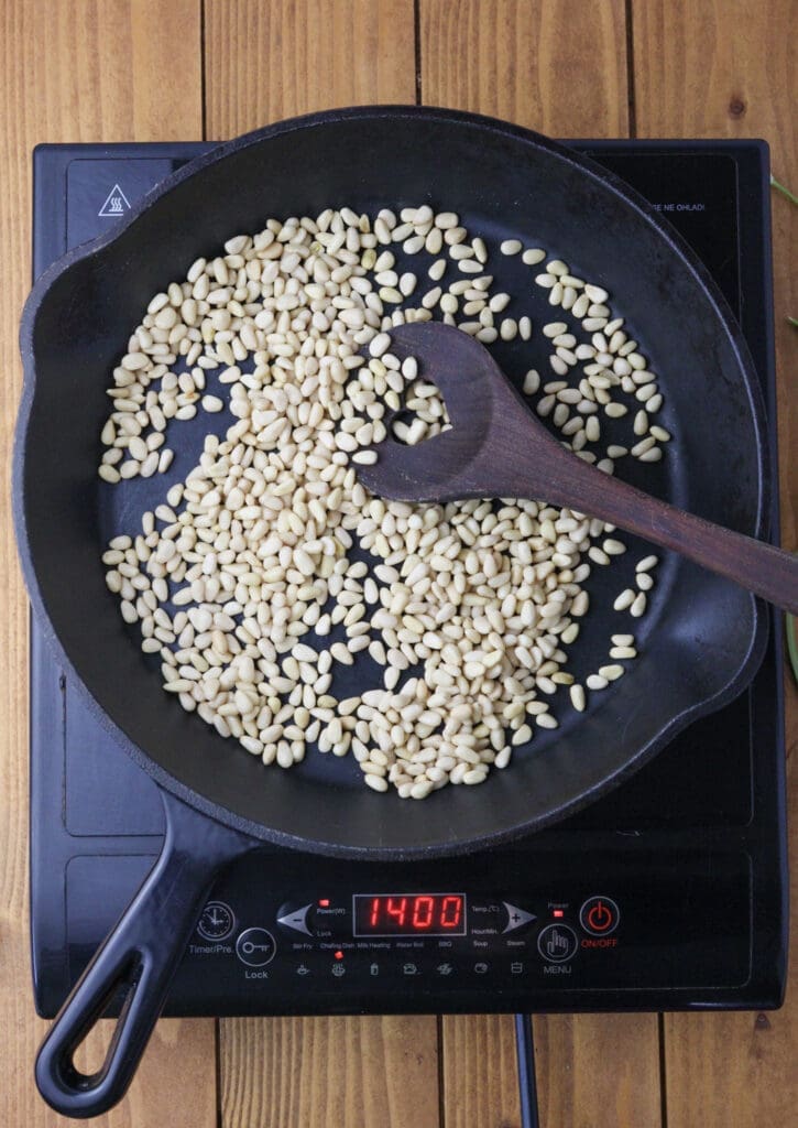 Pine nuts getting toasted in a cast iron skillet to release the aroma for a better pesto.