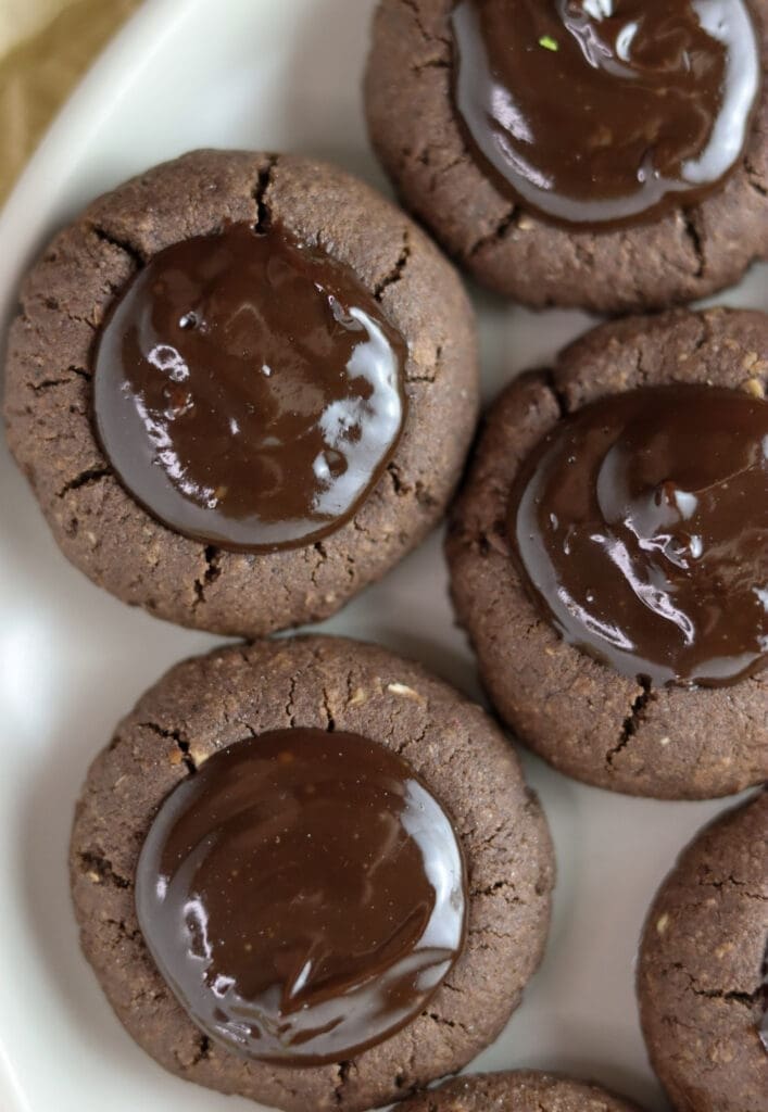 A close shot of three buckwheat thumprint cookies with chocolate.
