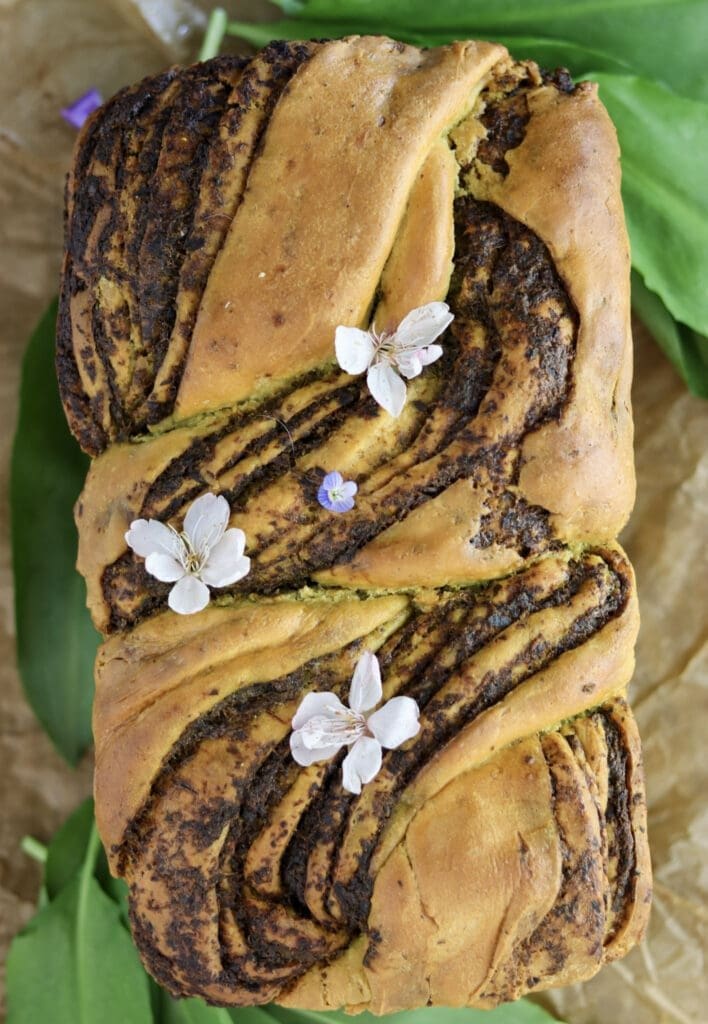 Freshly baked wild garlic babka bread loaf with cherry flowers on top.