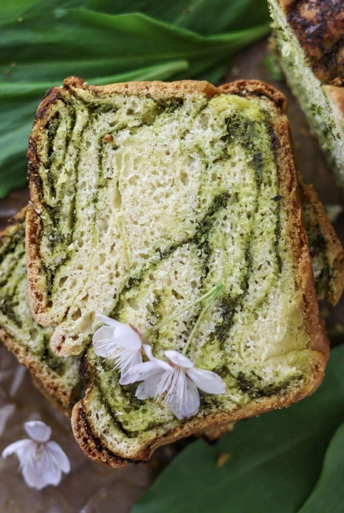 A delicious looking piece of wild garlic babka bread with wild garlic leaves in the background.